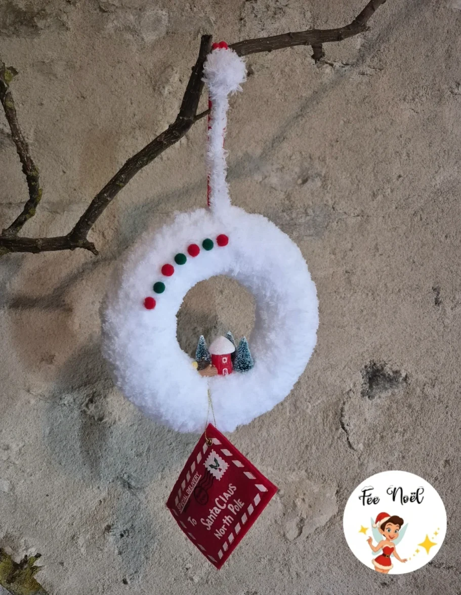 Couronne de Noël blanche décorée avec des perles et un petit personnage en bas.