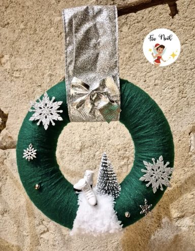Couronne de Noël verte avec flocons, sapin miniature et ornement argenté.