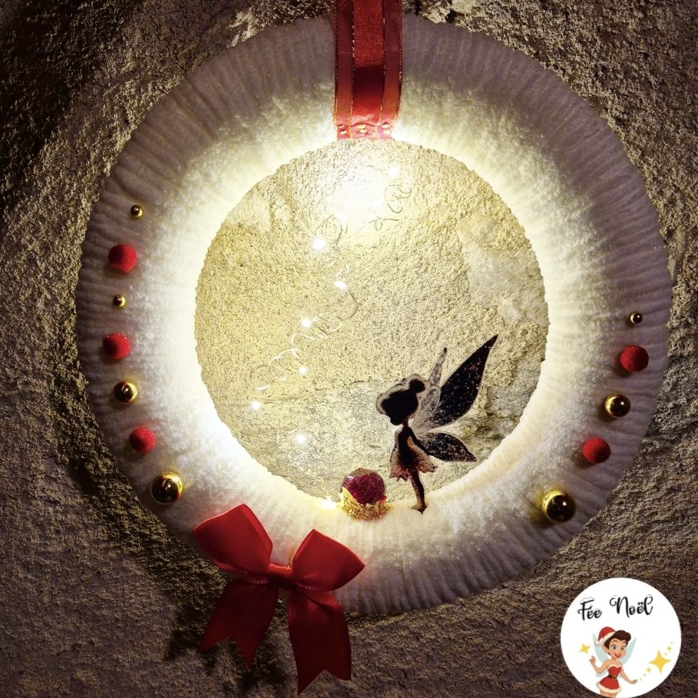 Couronne décorative avec une fée, des lumières et des embellissements festifs.