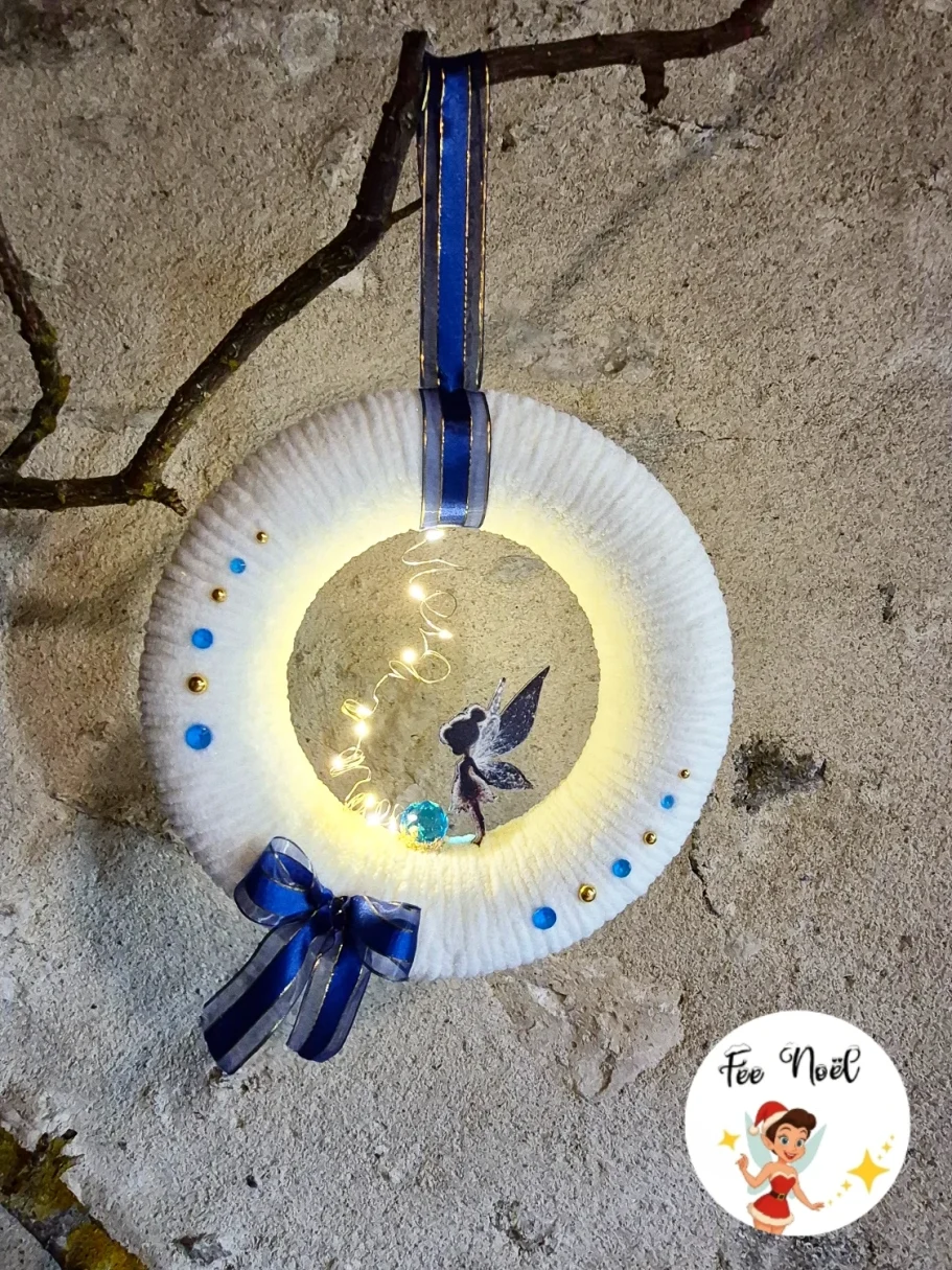 Couronne décorative blanche avec lumières, un oiseau et un ruban bleu.