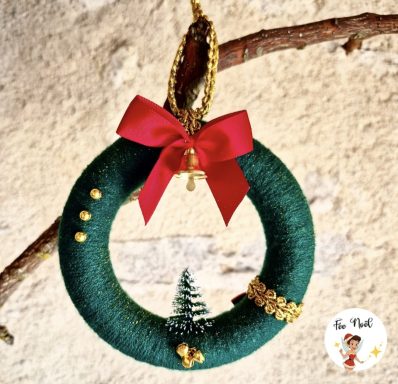Couronne de Noël verte avec un nœud rouge, un sapin et des décorations dorées.