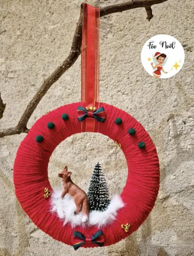 Couronne rouge décorée avec un sapin et un renne en peluche.