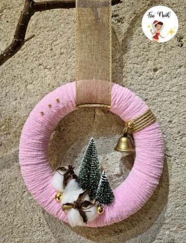 Couronne rose décorée de petits arbres, cloche et éléments en feutre.