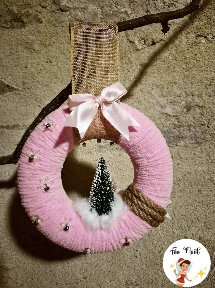 Couronne rose décorée avec un sapin miniature et un ruban.